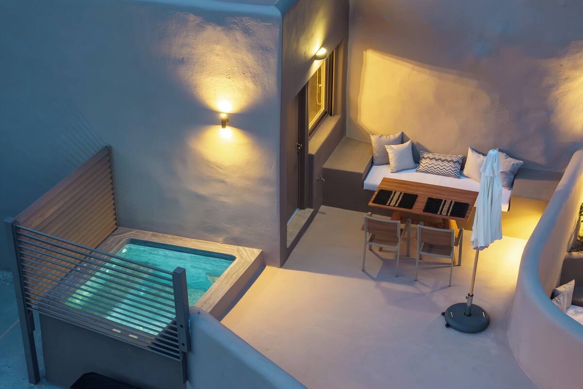 A modern outdoor seating area with a pool, a wooden table, and a sofa.