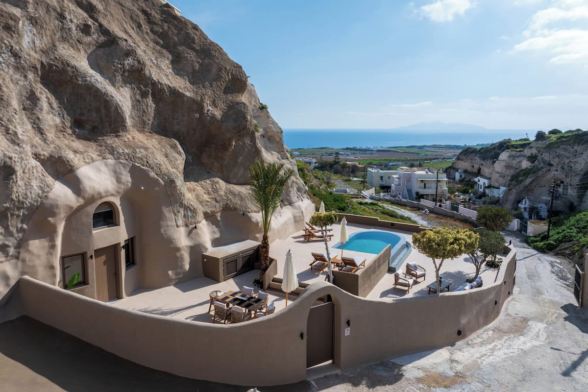 A cliffside hotel with a pool, lounge chairs, and a view of the sea.