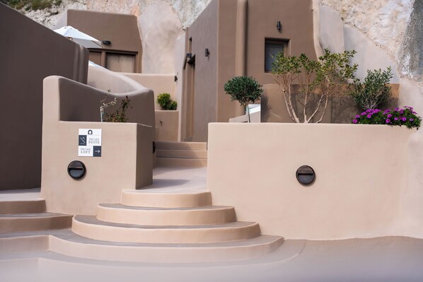 Un conjunto de escalones beiges y curvos que llevan a una puerta con un letrero que dice 'The Cave Suite'.