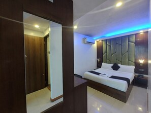 A modern bedroom with a bed, bedside tables, and a mirror. - Hotel Rio (Mumbai)