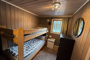 Ein Schlafraum mit Etagenbetten, einem Fenster, einem Spiegel und einem kleinen Schrank.