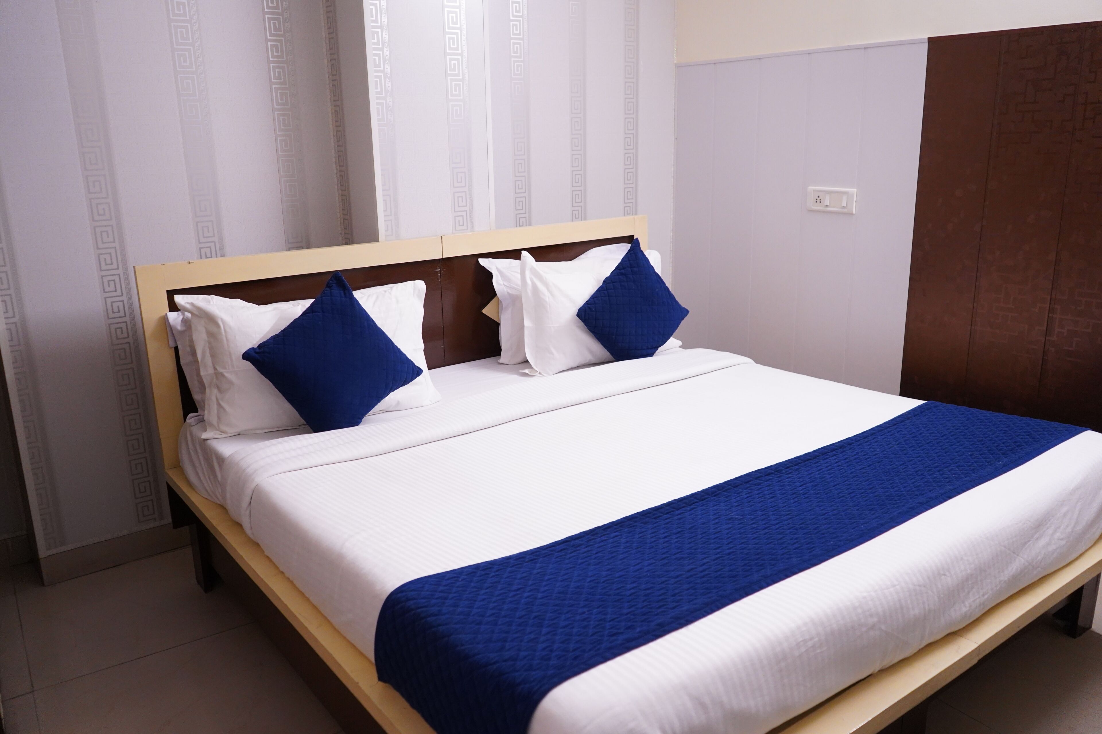 Una cama con estructura de madera, ropa de cama blanca y detalles en azul.