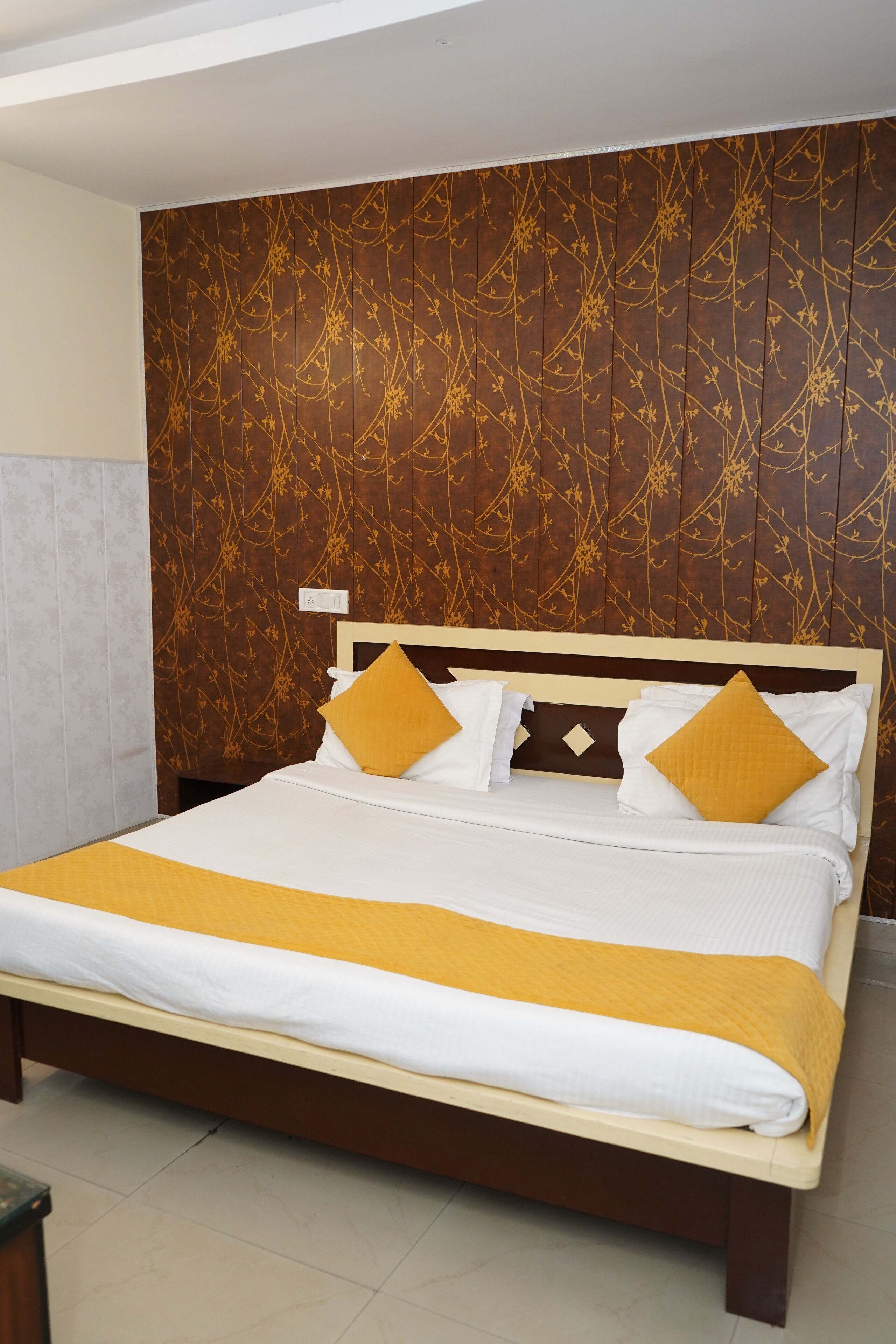 A neatly made bed with a wooden headboard, a yellow throw blanket, and two pillows.
