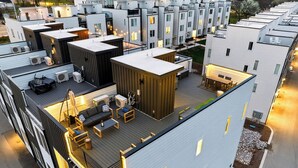 Ett modernt bostadskomplex med flera lägenheter, utomhusområden med sittplatser och en takterrass.
