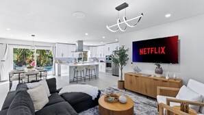 Una sala de estar moderna con un sofá negro, una mesa de centro de madera y un televisor de pantalla plana montado en la pared.