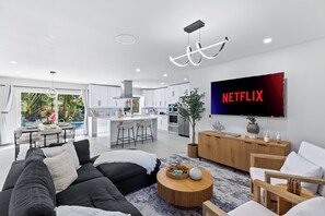 Ein modernes Wohnzimmer mit einer schwarzen Couch, einem Holztisch und einem flachbildfernseher an der Wand.