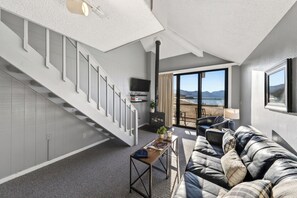 Ein modernes Wohnzimmer mit Treppe, Sofa, Couchtisch und Blick auf den Strand.