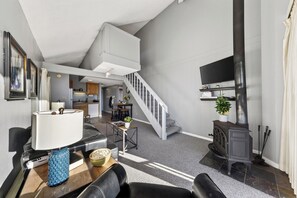 Ein modernes Wohnzimmer mit Kamin, Essbereich und einer Treppe zu einer oberen Ebene.