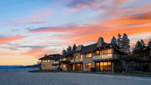 Un hôtel à plusieurs étages, doté de balcons, situé près d’une plage offrant une vue sur le coucher de soleil.