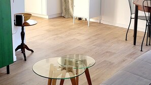 Ein Wohnzimmer mit einer Couch, einem Glastisch und einem Essbereich mit Stühlen.