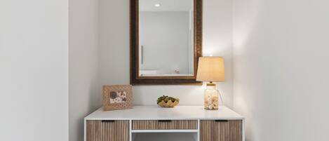A white desk with a mirror, a lamp, and decorative items.