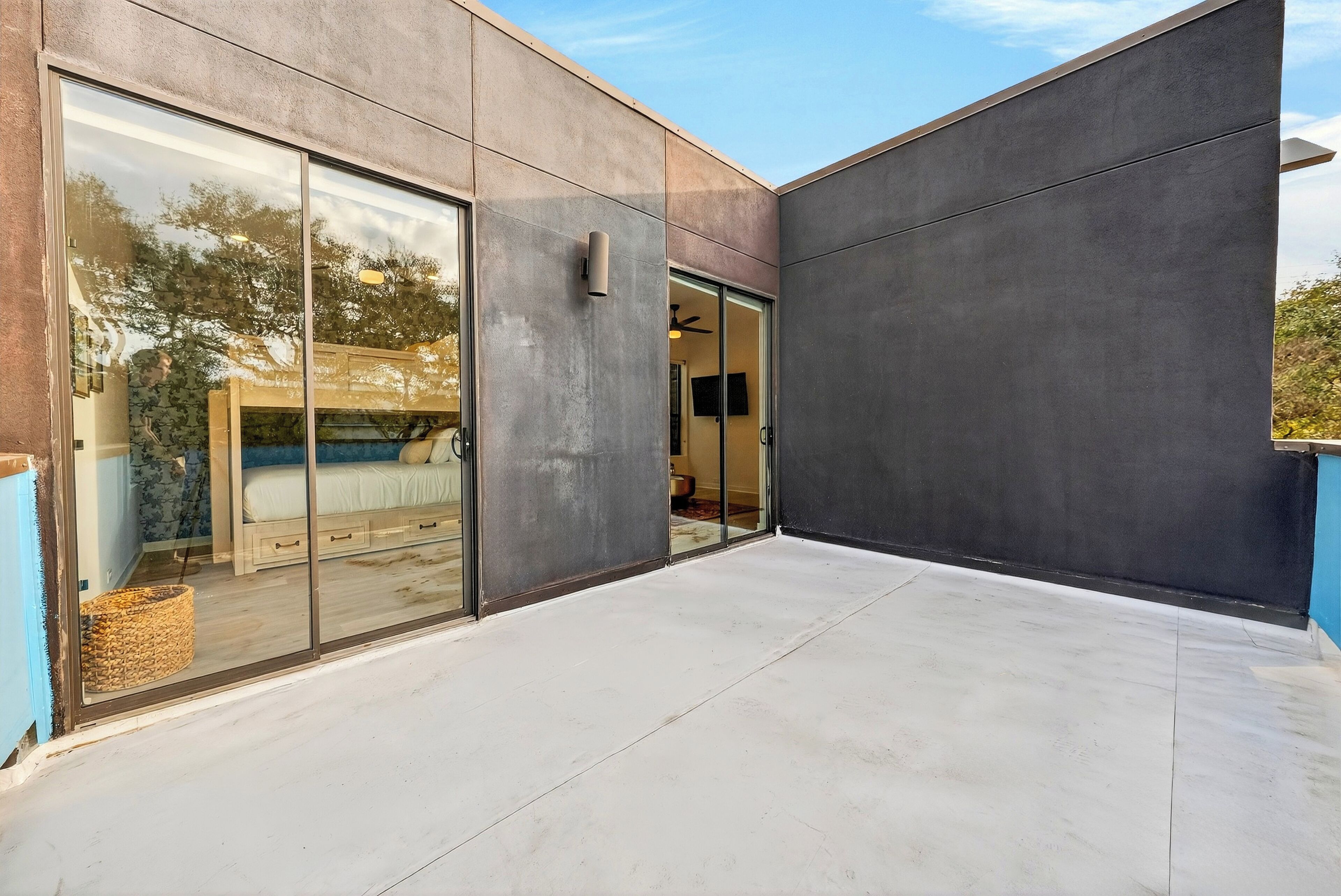A modern building with large sliding glass doors leading to a bedroom with a bed and a television.