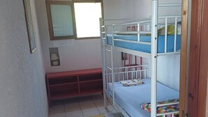 Una habitación pequeña con literas, un banco, una ventana y una alfombra.