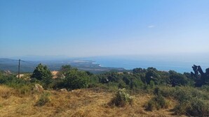 Paisaje costero con cielo despejado, vegetación y formas de tierra a lo lejos.