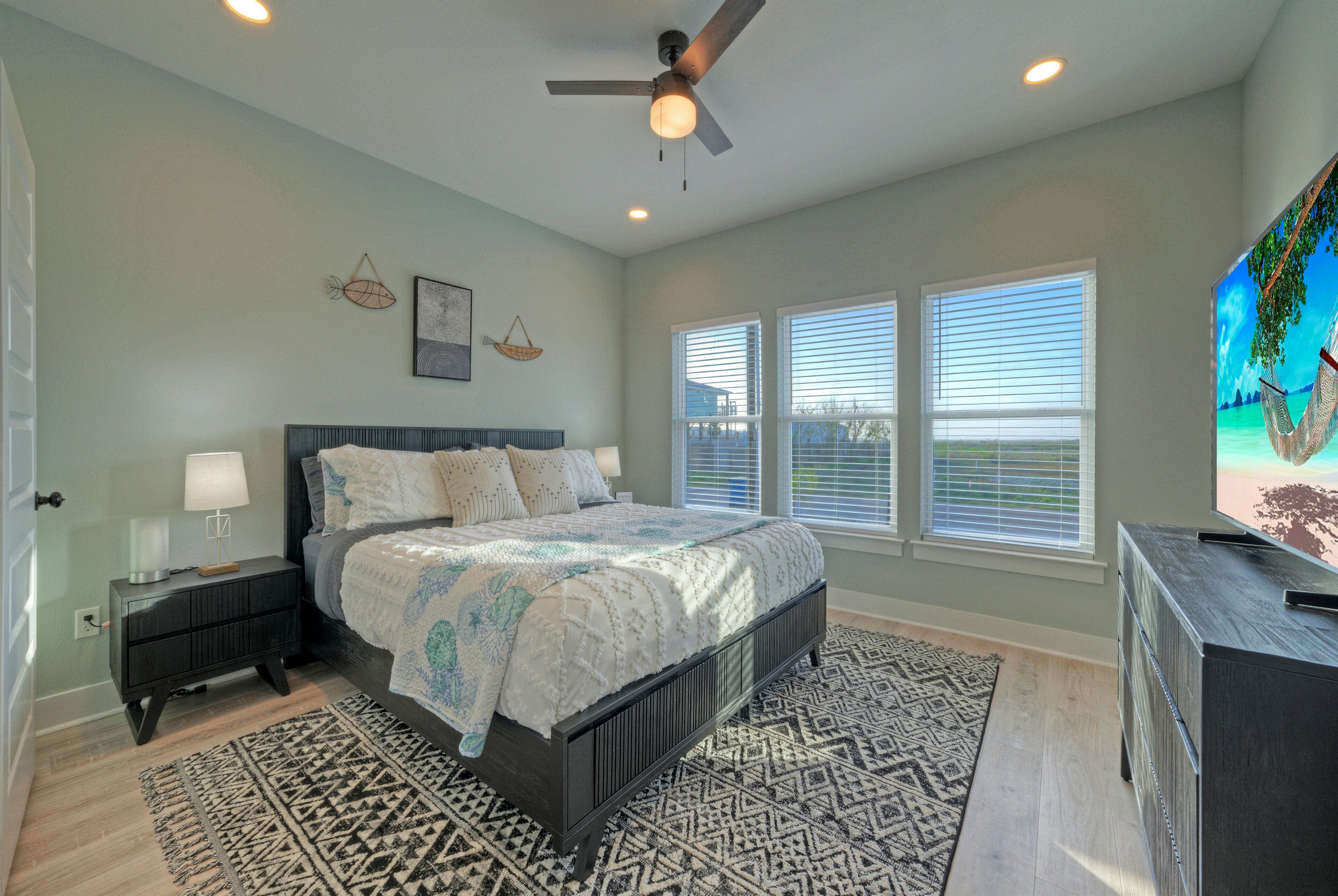 A bedroom with a bed, nightstand, dresser, and a ceiling fan.