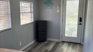 A bedroom with a bed, a dresser, a door with frosted glass, and a wall with a motivational quote. - Cozy 2-bedroom cabin in peaceful Tow with AC (Tow)