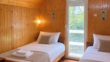 Habitació amb dos llits, parets de fusta, una porta que dona a l'exterior i un petit lluminari fixat a la paret.