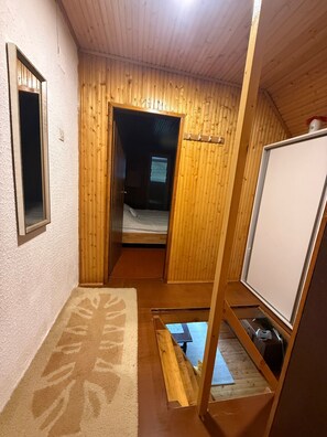 Habitación pequeña con cama, una mesita y una pizarra.