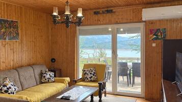 A wooden-paneled room with a sofa, armchairs, a coffee table, and a television.