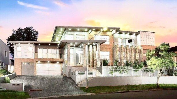 A modern two-story building with a garage, a staircase, and a well-maintained lawn.