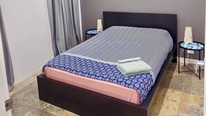 A modern bedroom with a bed, two bedside tables, a nightstand, and a window with curtains.