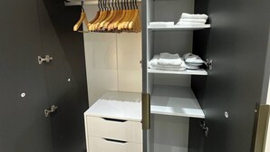 Un dressing accessible sans porte, doté d’une porte-miroir, de nombreuses étagères et d’un espace pour suspendre les vêtements.