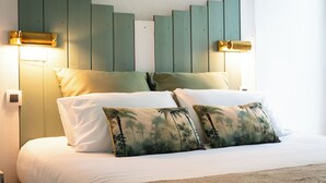 A bed with white linens, two pillows with a palm tree design, and a headboard with vertical wooden slats. - Le Parasol (Ars-en-Ré)