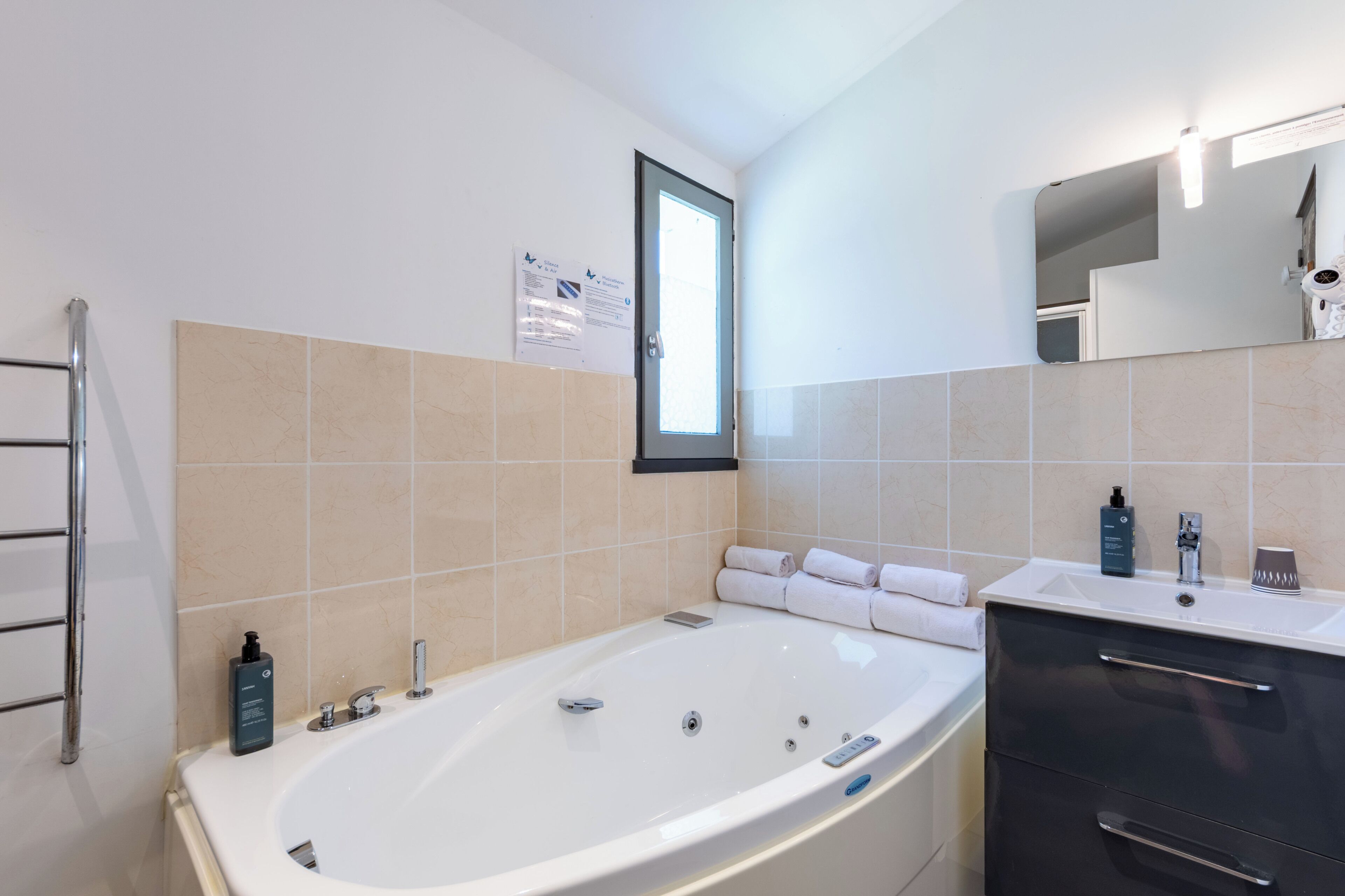 A modern bathroom with a freestanding bathtub, a vanity with a mirror, and a towel rack.