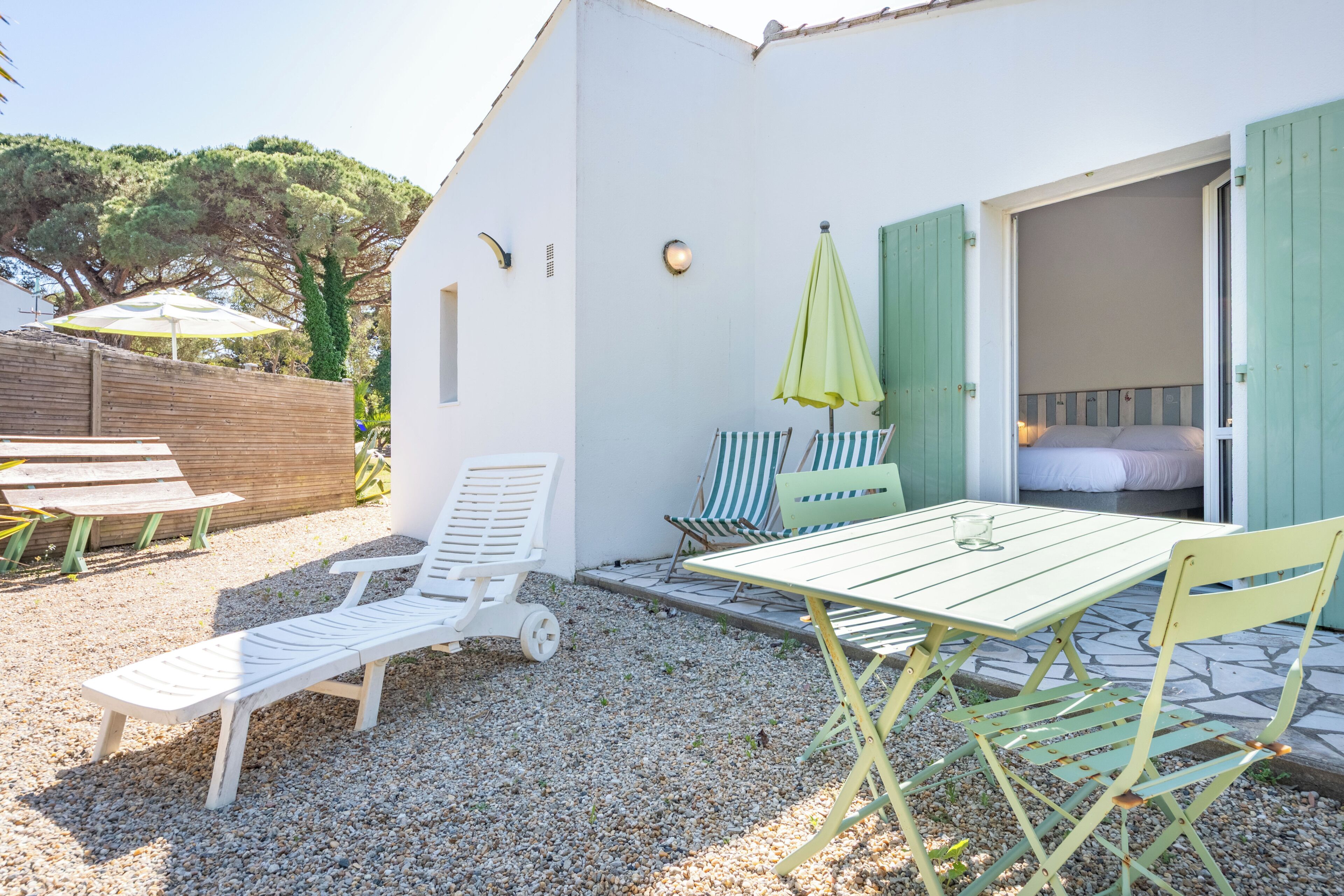 Un edificio blanco con un patio que incluye una mesa, sillas y una tumbona.