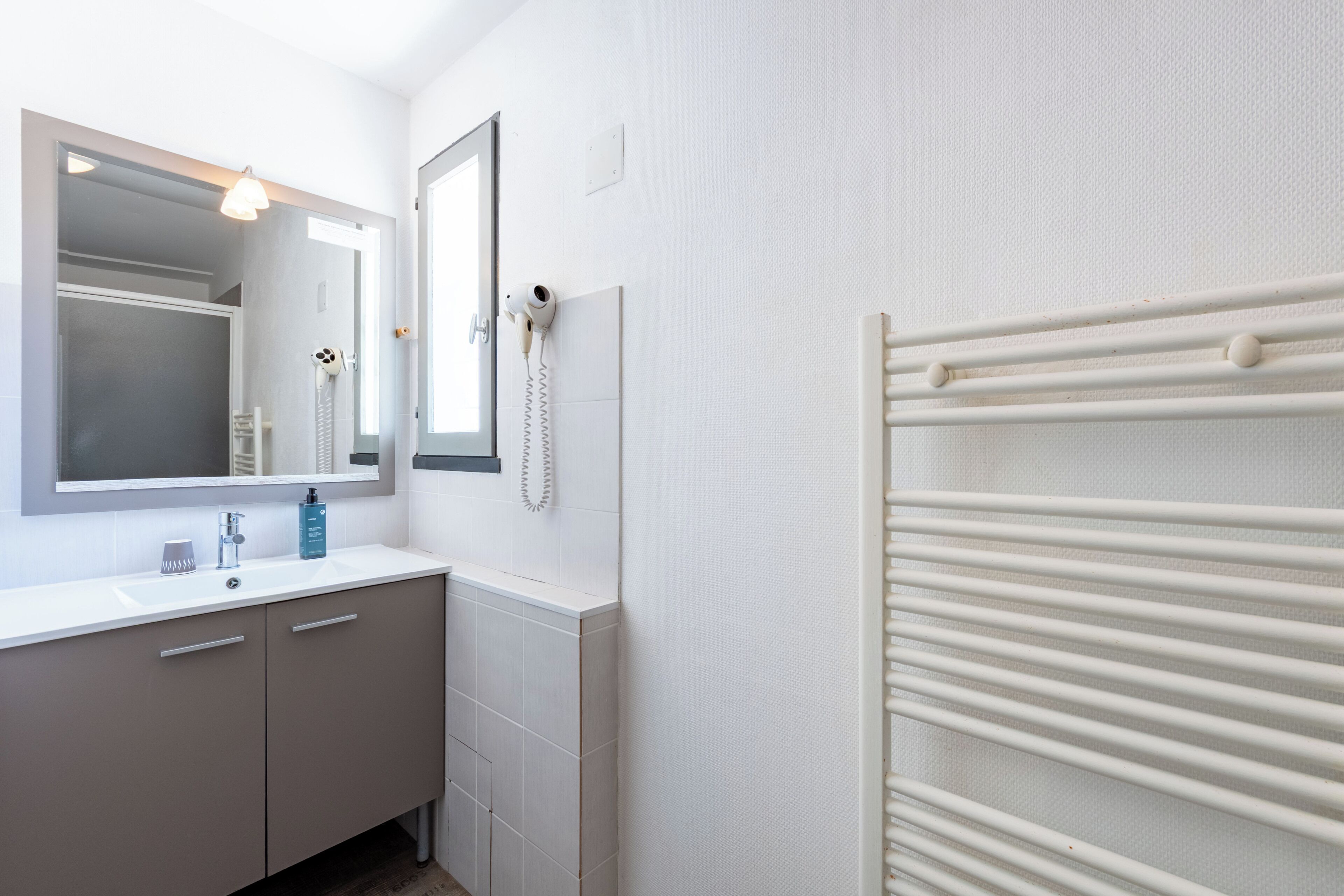 A bathroom with a white sink, mirror, and towel rack.