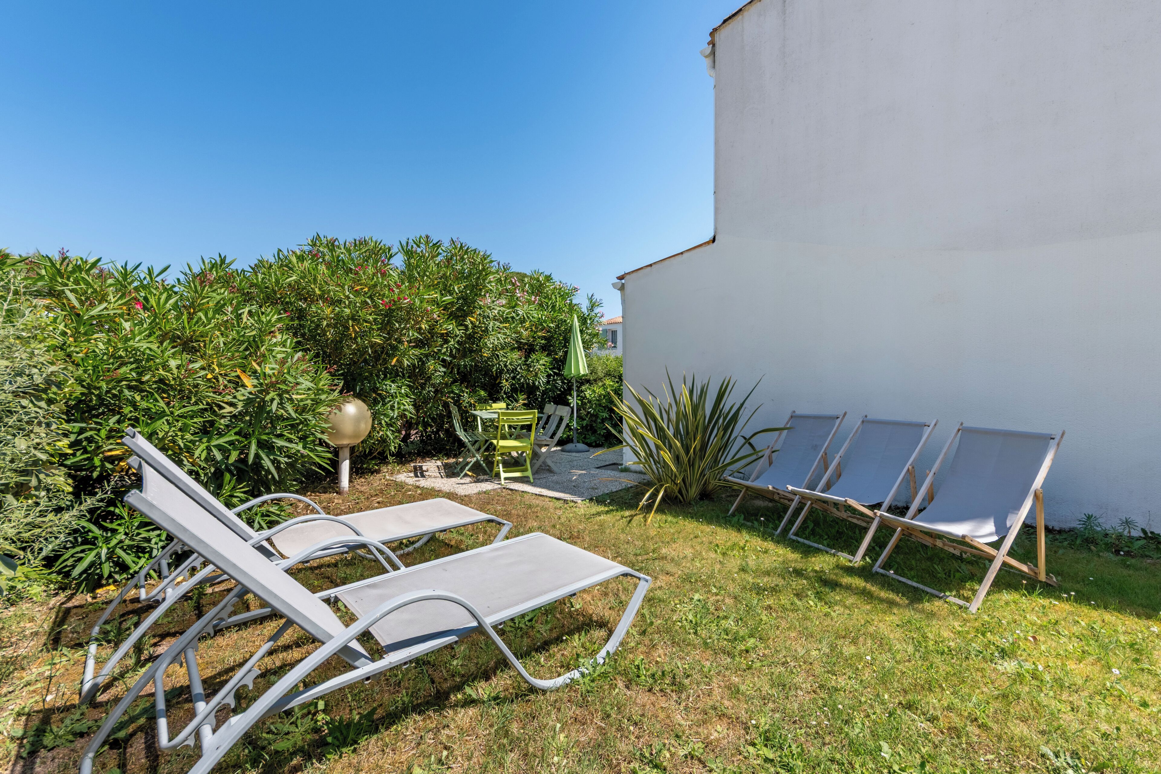 A garden with outdoor seating and a white wall.