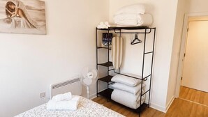 Ein Schlafzimmer mit einem Bett, einem Heizkörper, einer Hängelampe, einem Kleiderschrank und einer Tür.