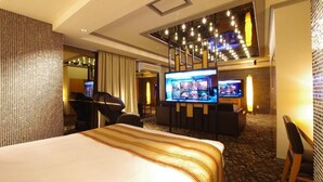 A hotel room with a large bed, a TV, a seating area, and a staircase.