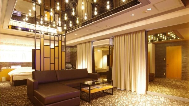 A hotel room with a sofa, a coffee table, a bed, and a large mirror.