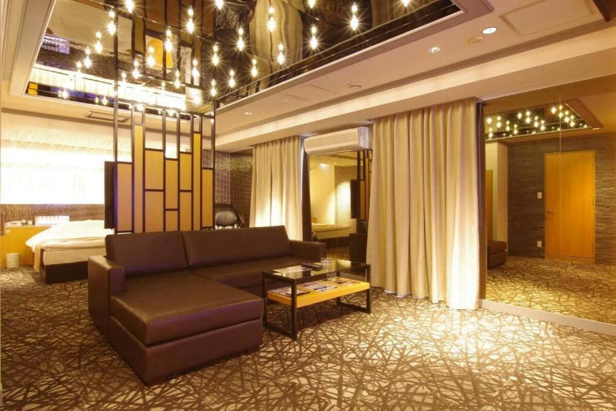 A hotel room with a sofa, a coffee table, a bed, and a large mirror.