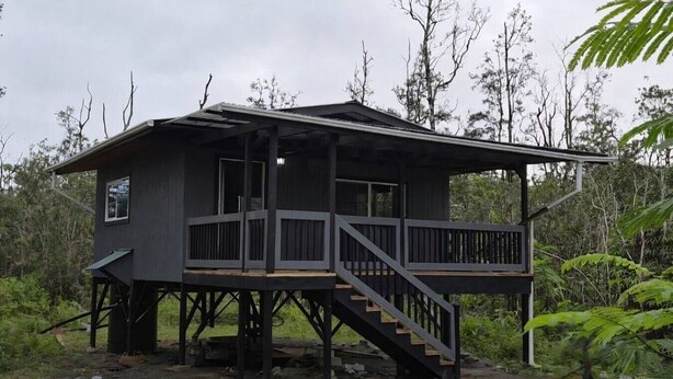 A wooden cabin with a balcony and stairs, surrounded by dense vegetation. - Jungle Lux Cabin - Private Retreat w/ AC & WiFi (Keaau)