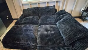 A sectional sofa with a dark, textured upholstery in a room with wooden flooring and a window with a view. - Jungle Lux Cabin - Private Retreat w/ AC & WiFi (Keaau)