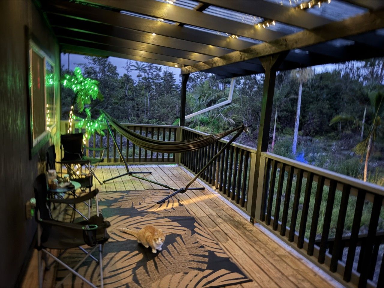 A wooden deck with a hammock, chairs, and a small table.