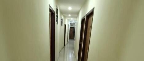 A long, narrow hallway with doors on both sides, leading to a room at the end.