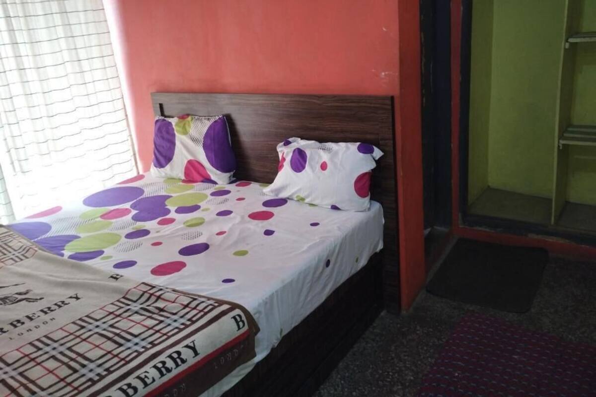 A bed with a polka dot bedspread, a pillow with a similar pattern, and a headboard.