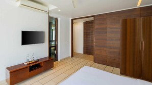 Ein Schlafzimmer mit einem Bett, einem Fernseher, einem Holzschrank und einem Schiebetürenschrank.