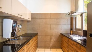 Eine kompakte Küche mit integriertem Wasserspender, einer Edelstahl-Spüle und Holzschränken.