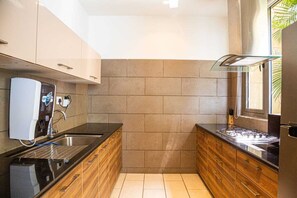 Eine kompakte Küche mit integriertem Wasserspender, einer Edelstahl-Spüle und Holzschränken.