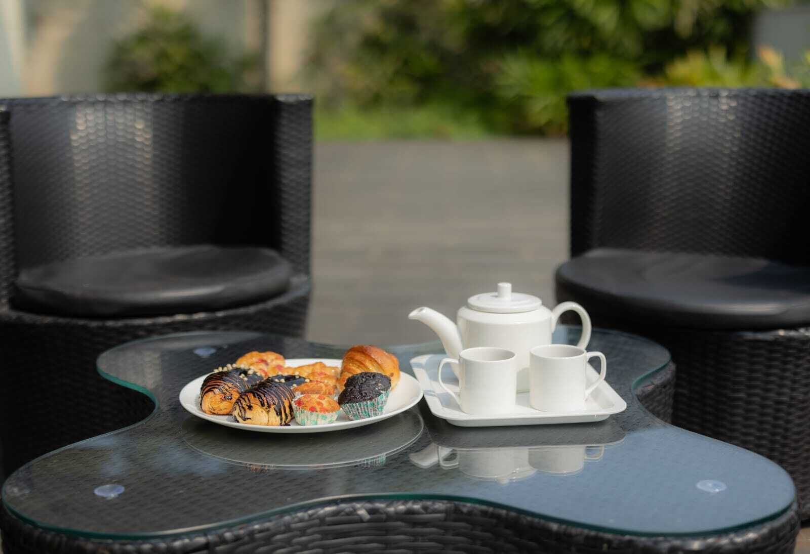 A table with a teapot, cups, and pastries.