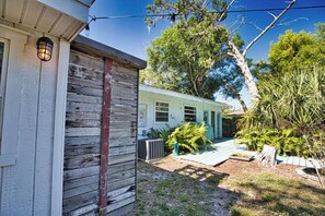 Uma casa rústica com fachada de madeira, varanda e um jardim bem cuidado com diversas plantas.