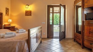 Ein Schlafzimmer mit einem Bett, einer Nachttischlampe, einem Holzschrank und einer Tür zu einem Außenbereich.