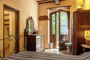 Une chambre à coucher comprenant un lit, une commode, un miroir et une porte donnant sur un balcon.