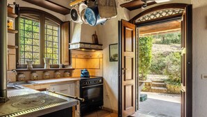 A kitchen with a stove, hanging pots, and a window with a view of greenery. - Vacation Home in Perugia with 3 bedrooms sleeps 7 (Perugia)