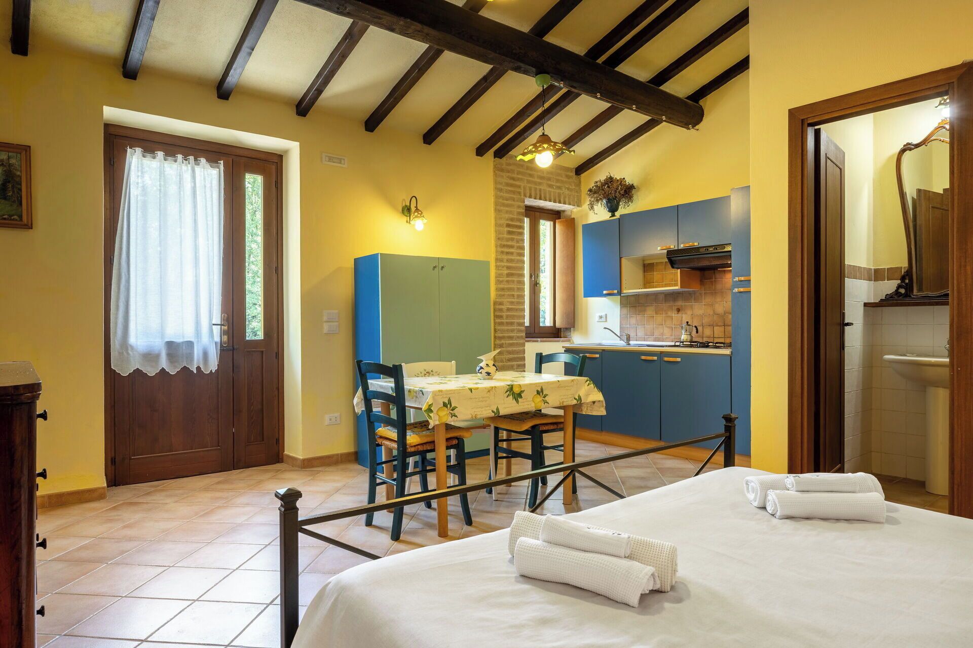 A room with a bed, a table with chairs, a kitchen area, and a bathroom.