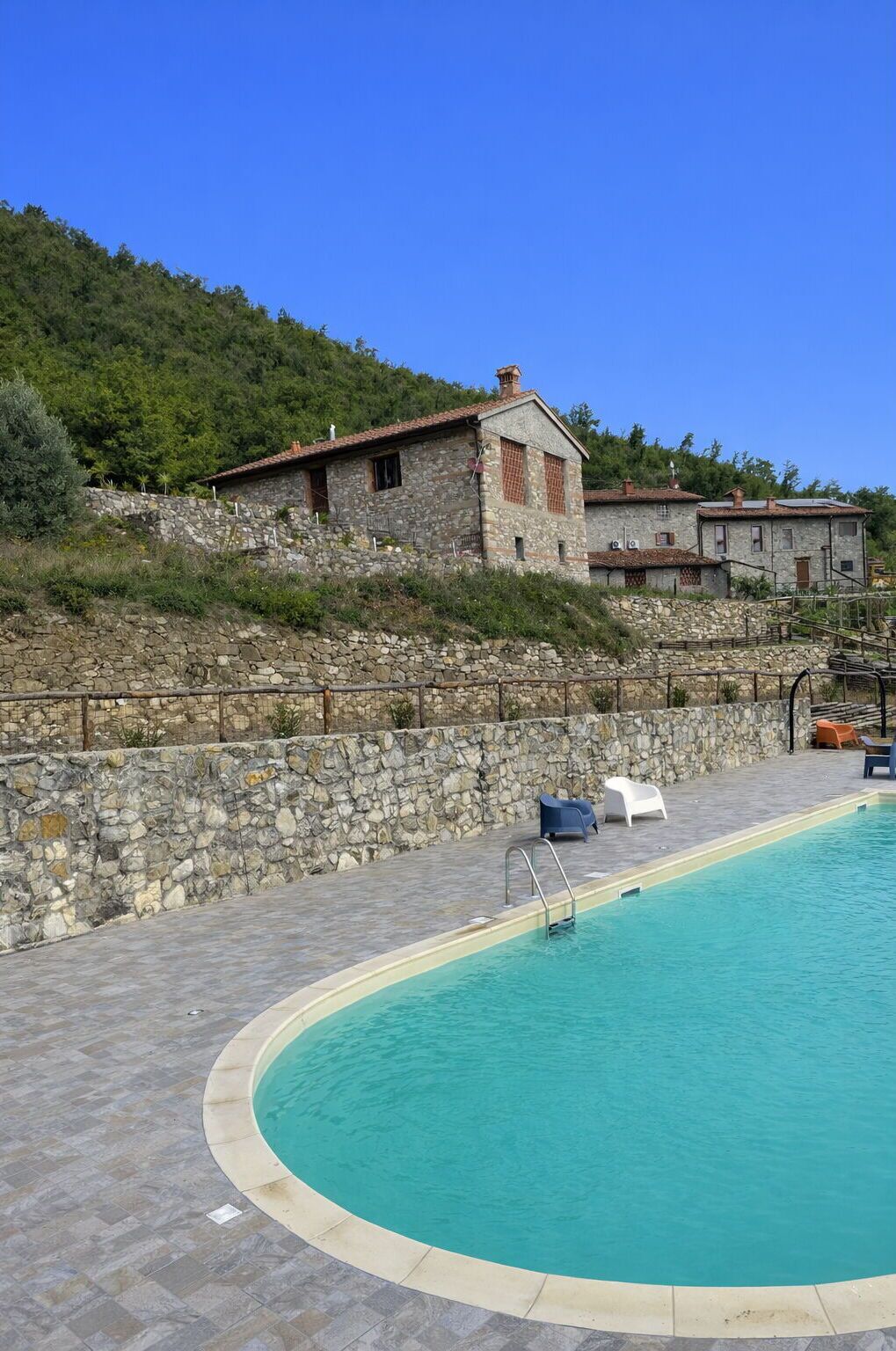 A stone building with a pool and lounge chairs.